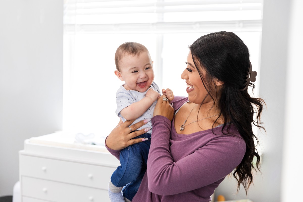 A baby laughing in a woman's arms