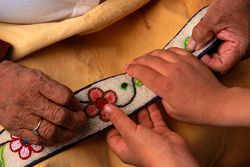 woman and child hands holding beaded cloth