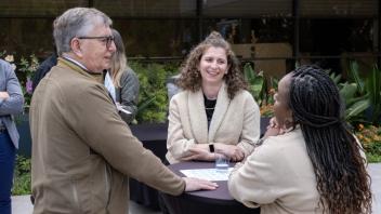 A group of Title IV-E Summit attendees gather around an outdoor table during a networking activity