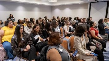 A group of Title IV-E Summit attendees gather in a seminar room for a presentation.