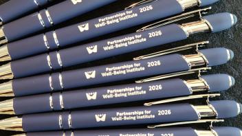 Blue promotional ballpoint pens with white logo, lined diagonally on dark fabric