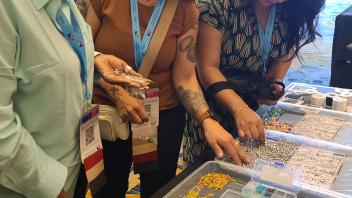 Four women with lanyards focused on colorful mosaic tiles at a craft table