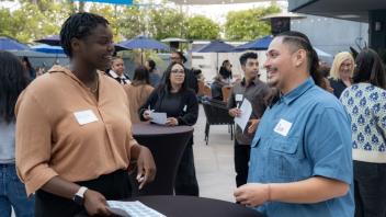 Two Title IV-E Summit attendees gather around an outdoor table during a networking activity