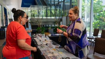 Two women talking over a table of craft supplies