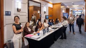 Conference registration table with smiling staff in hotel hallway