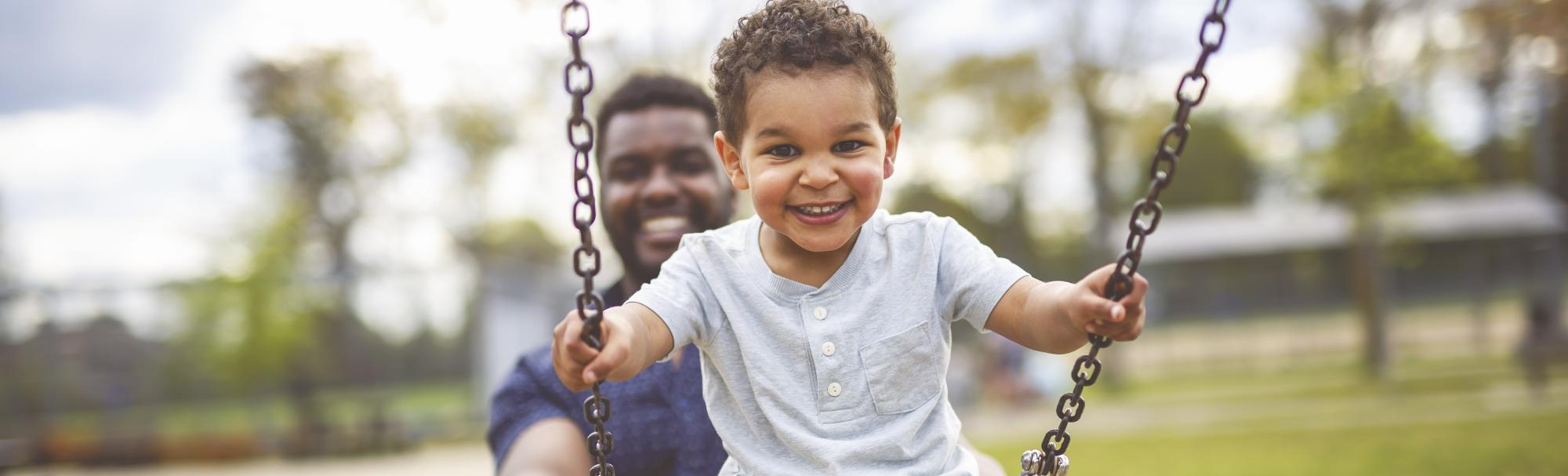 Dad pushing his son on a swing