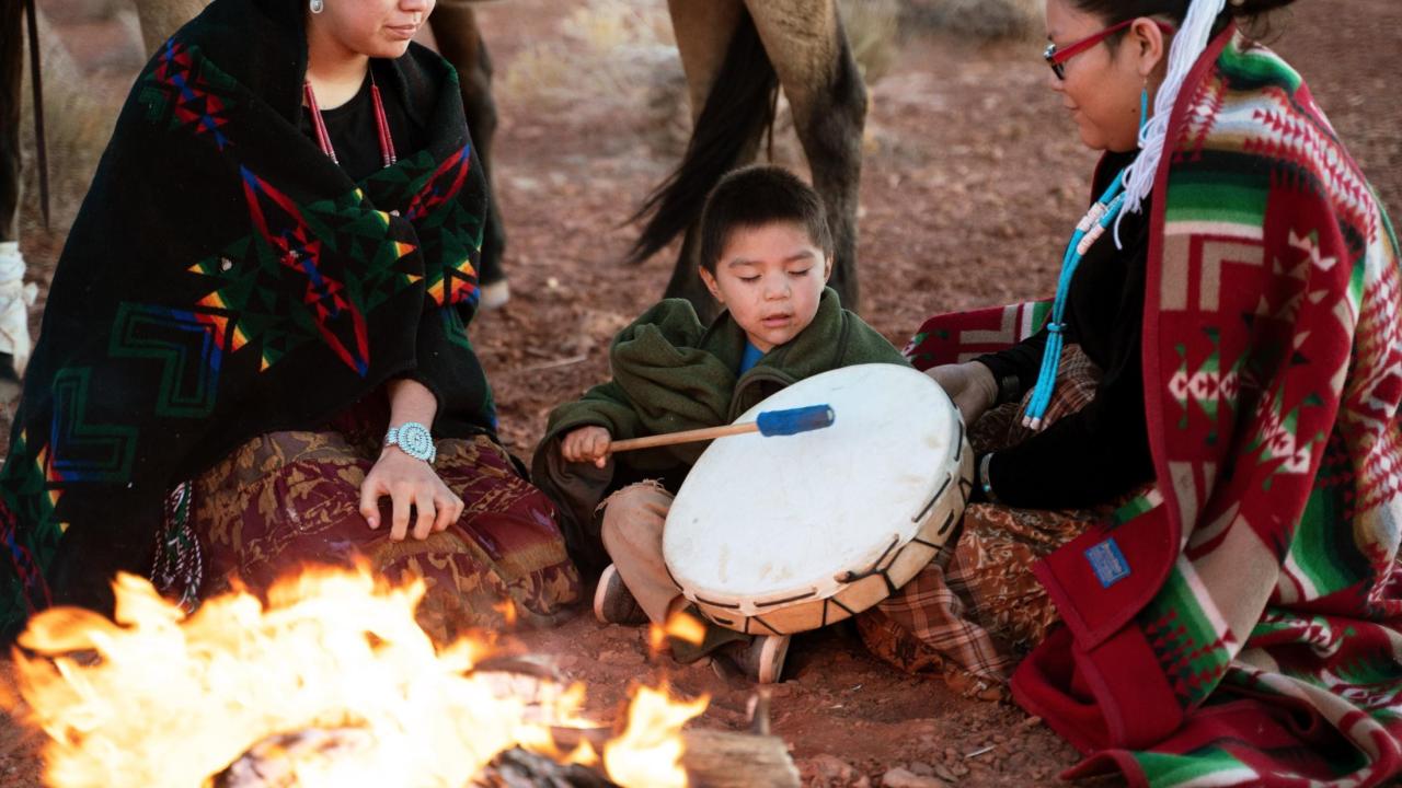 Native American grandmother teaching grandson to play drum