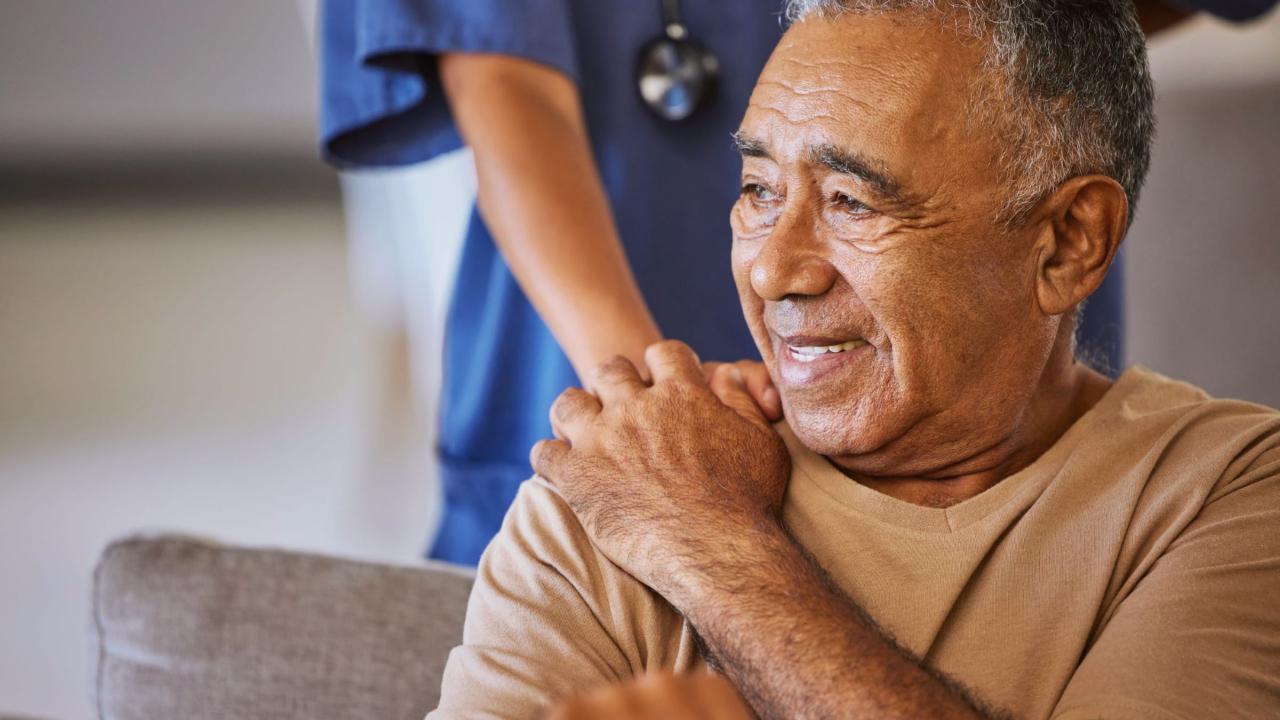 An elderly man being assisted by a helping hand.