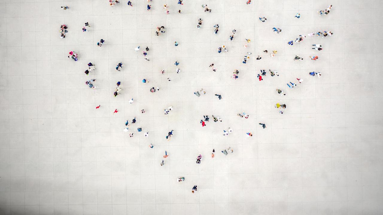 A group of people standing together in the collective shape of a heart.