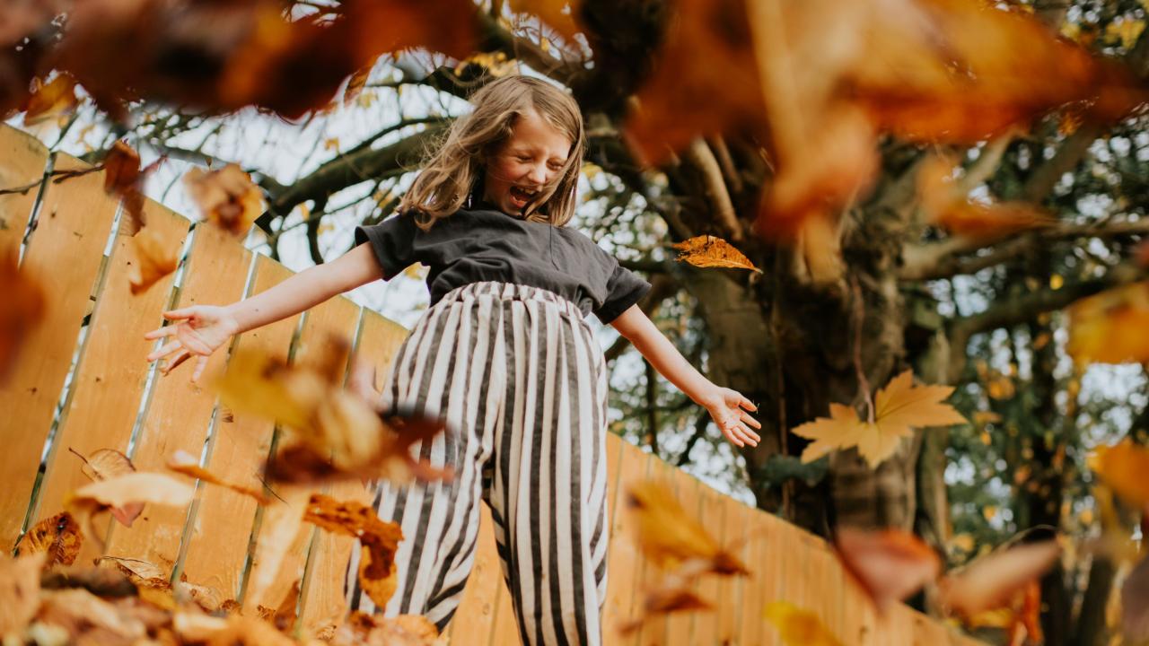 A girl jumping for joy in falling leaves