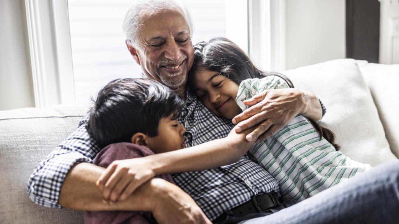 Grandfather hugging his two grandkids on the couch