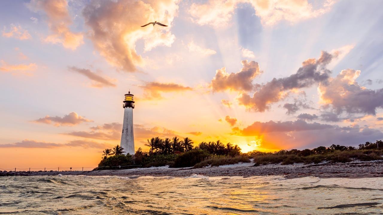 A lighthouse during sunset or sunrise over water.