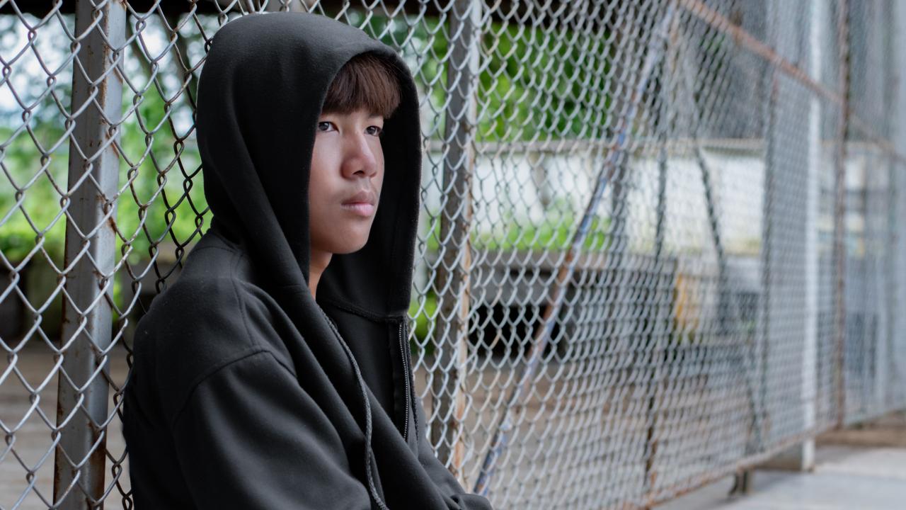 Youth sitting near fence