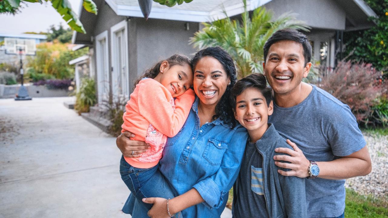 Happy family standing outside their home