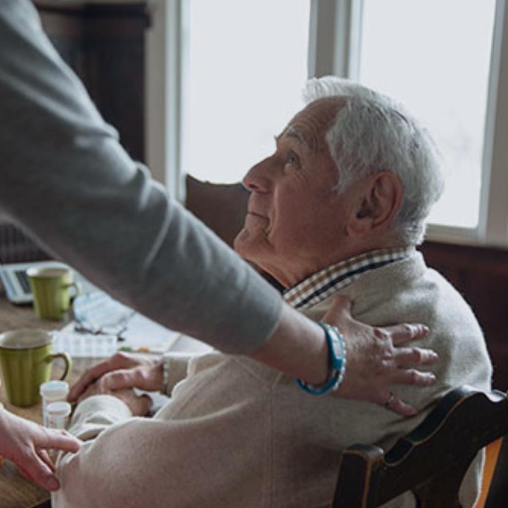 An elderly man being assisted by a helping hand.