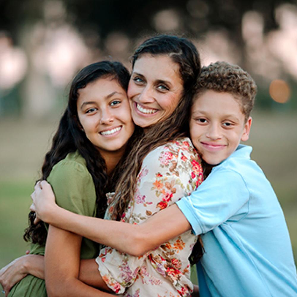 A woman embraced by two children.