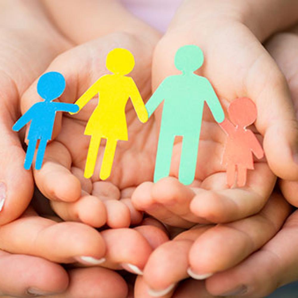 Overlapping hands holding a colorful cutout of a family.