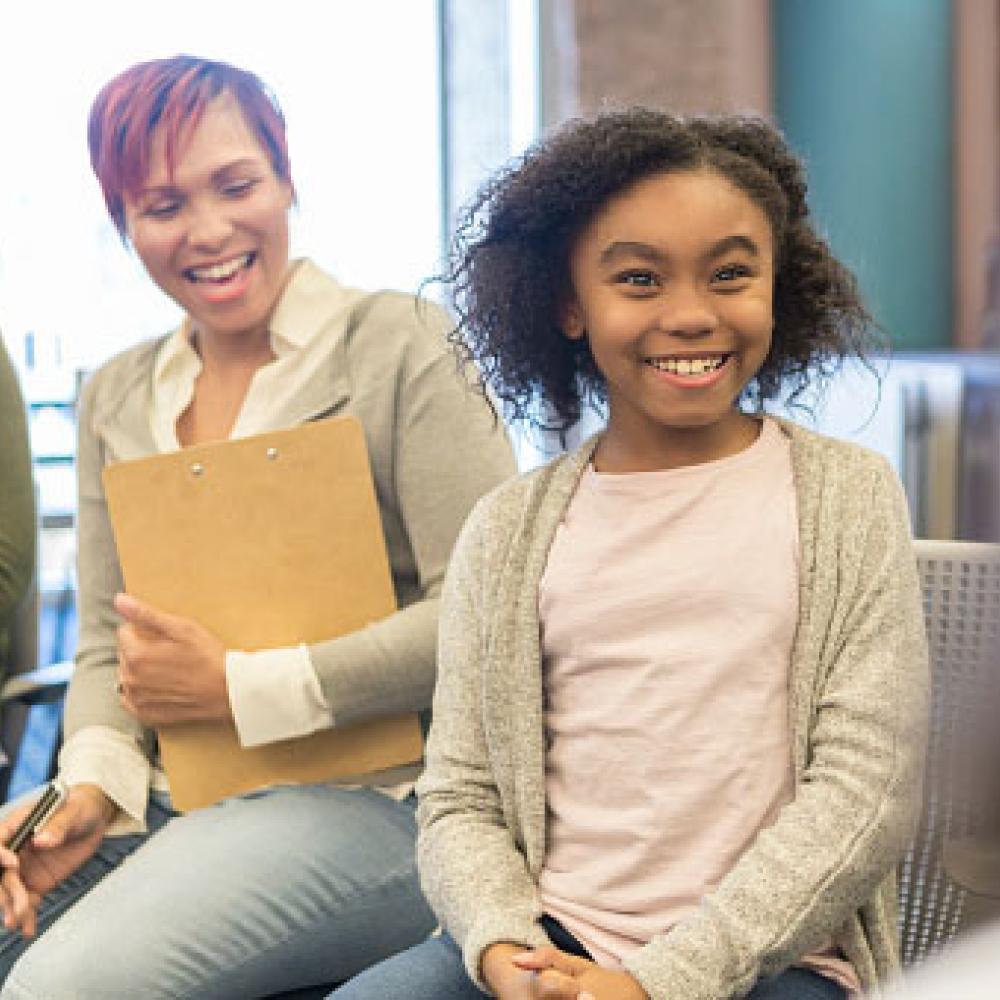 Two smiling adults with a happy young girl.