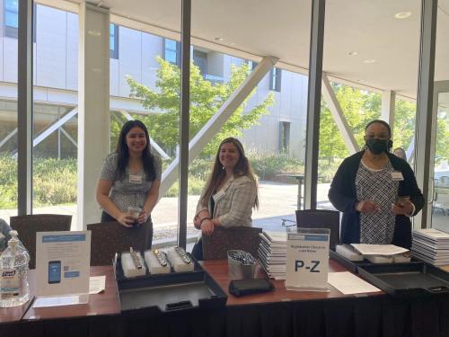 Three people standing at a registration table with welcoming smiles