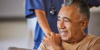 An elderly man being assisted by a helping hand.