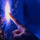 A finger touching a spark as though to symbolize breaking through a barrier