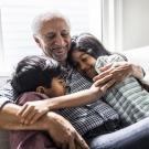 Grandfather hugging his two grandkids on the couch