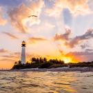 A lighthouse during sunset or sunrise over water.