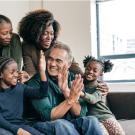 Smiling multigenerational family gathers on a couch and give each other high-fives.