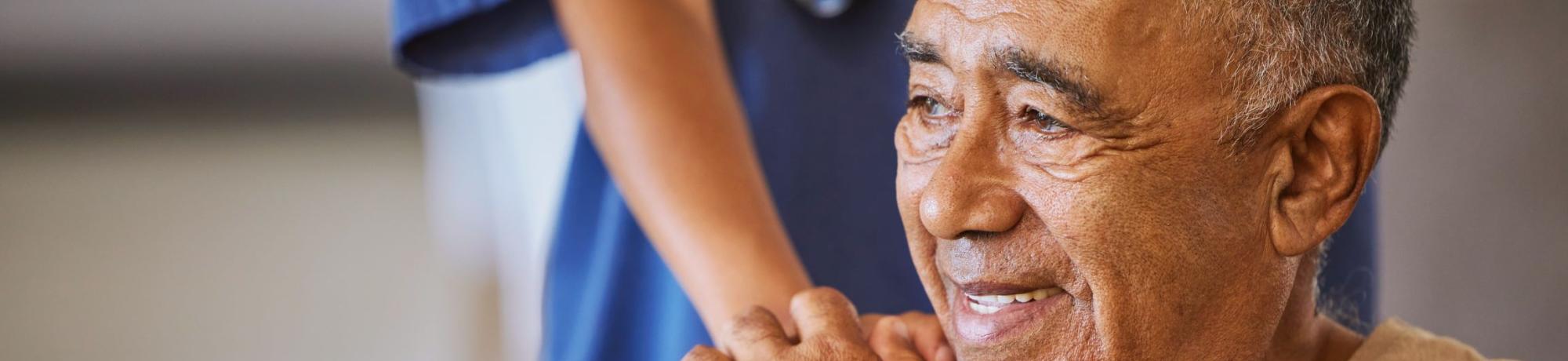 An elderly man being assisted by a helping hand.
